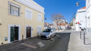 Une ruelle étroite pavée, bordée de bâtiments des deux côtés, avec une voiture garée et un ciel bleu dégagé.