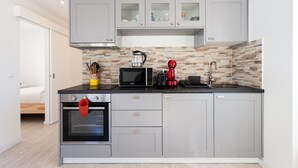 Une cuisine moderne avec des meubles gris, un four à micro-ondes, une bouilloire et une machine à café.