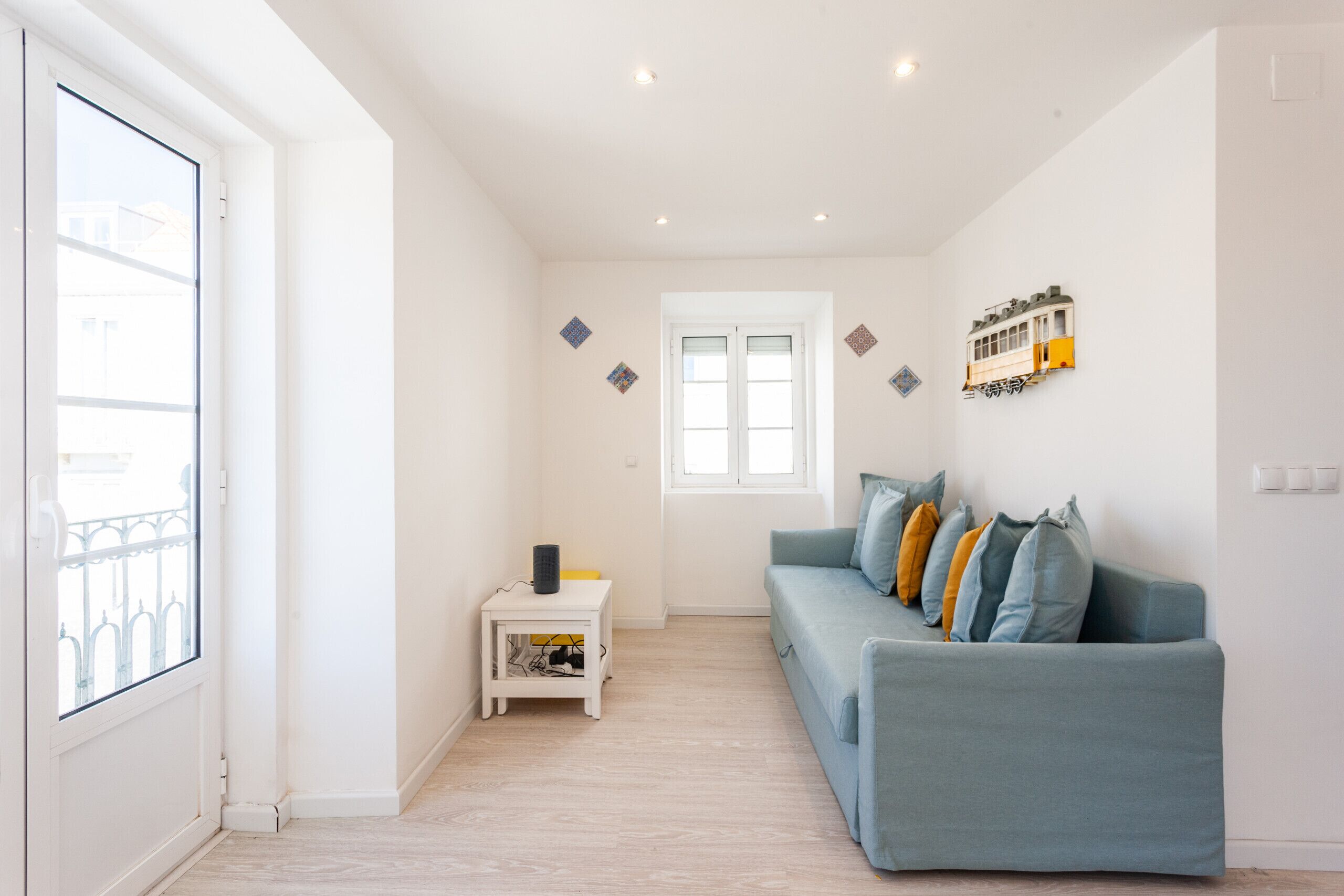 A modern living room with a light blue sofa, a small white side table, and a window with a view.