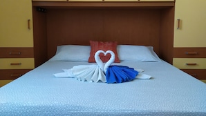 A hotel room with a bed, a heart-shaped towel arrangement, and a red pillow. - Vailletta Fiorita (Rome)