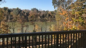 A view from a deck overlooking a lake with trees in the background.