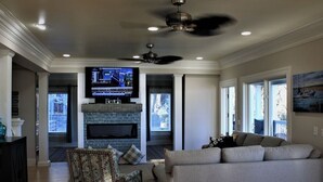 Una sala de estar con chimenea, televisor, sofá y ventilador de techo.