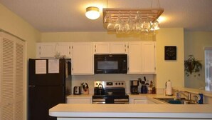 A compact kitchen with a refrigerator, microwave, stove, and sink. - The Colony III 204 - Walk to beach in Surfside Beach (Surfside Beach)