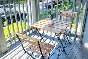 A wooden outdoor table and bench set on a porch with a potted plant.