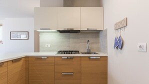 Eine moderne Küche mit Holzausstattung, einer Edelstahlspüle und einem Gasherd.