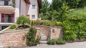 Ein mehrstöckiges Gebäude mit einer Steinmauer, einem Metallgitter und einem Balkon mit roten Fensterläden.