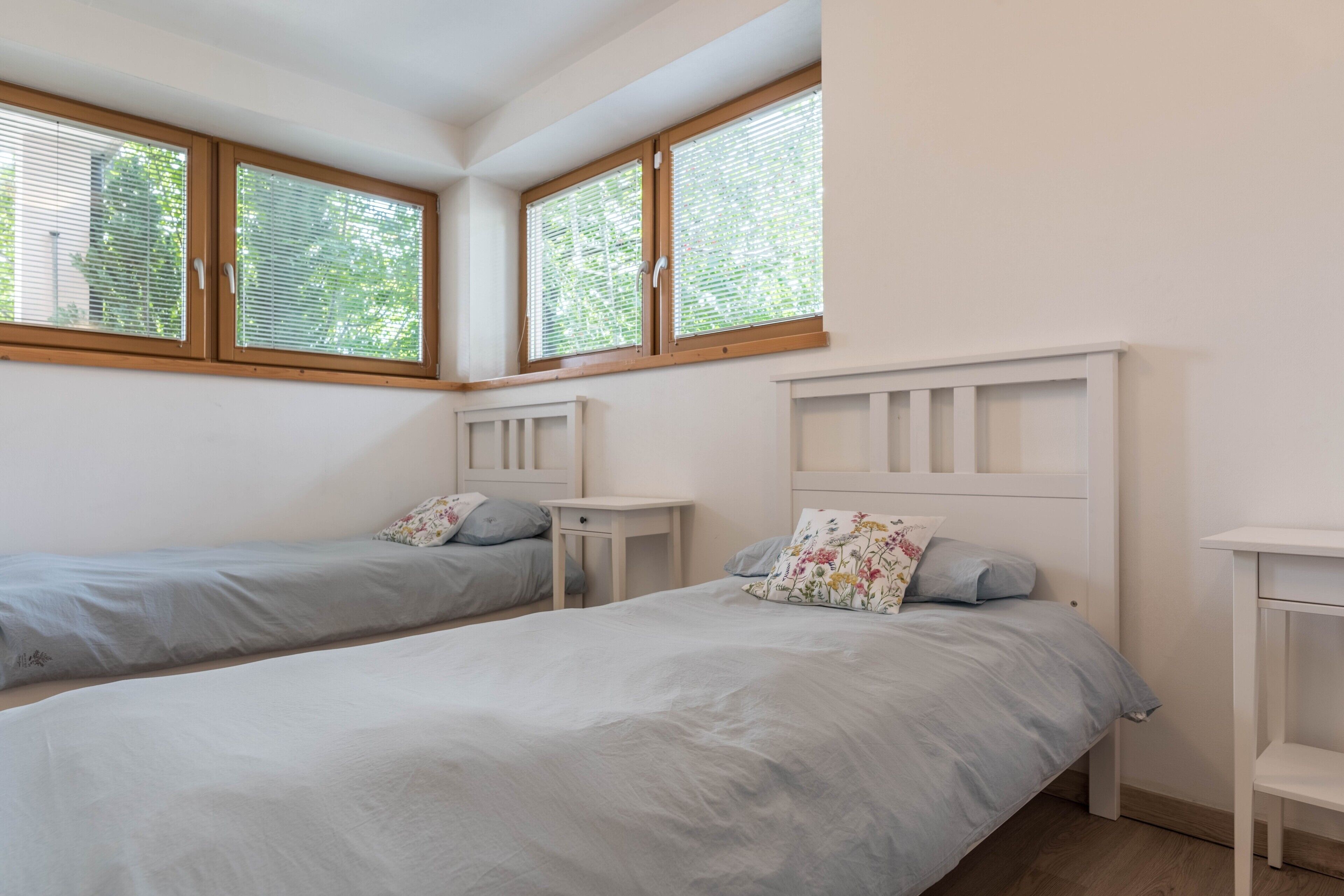 A bedroom with two beds, a window, and a white headboard.