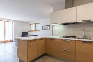 A modern kitchen with a central island, stainless steel appliances, and wooden cabinetry. - Cozy Apartment "Casa Weekend" with Lake and Mountain Views and Wi-Fi (Novella)