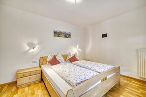 A bedroom with a wooden bed, a nightstand, a wall-mounted light, and a picture on the wall.