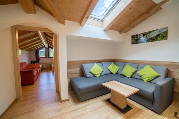 A modern living room with a grey sectional sofa, a wooden coffee table, and a skylight.