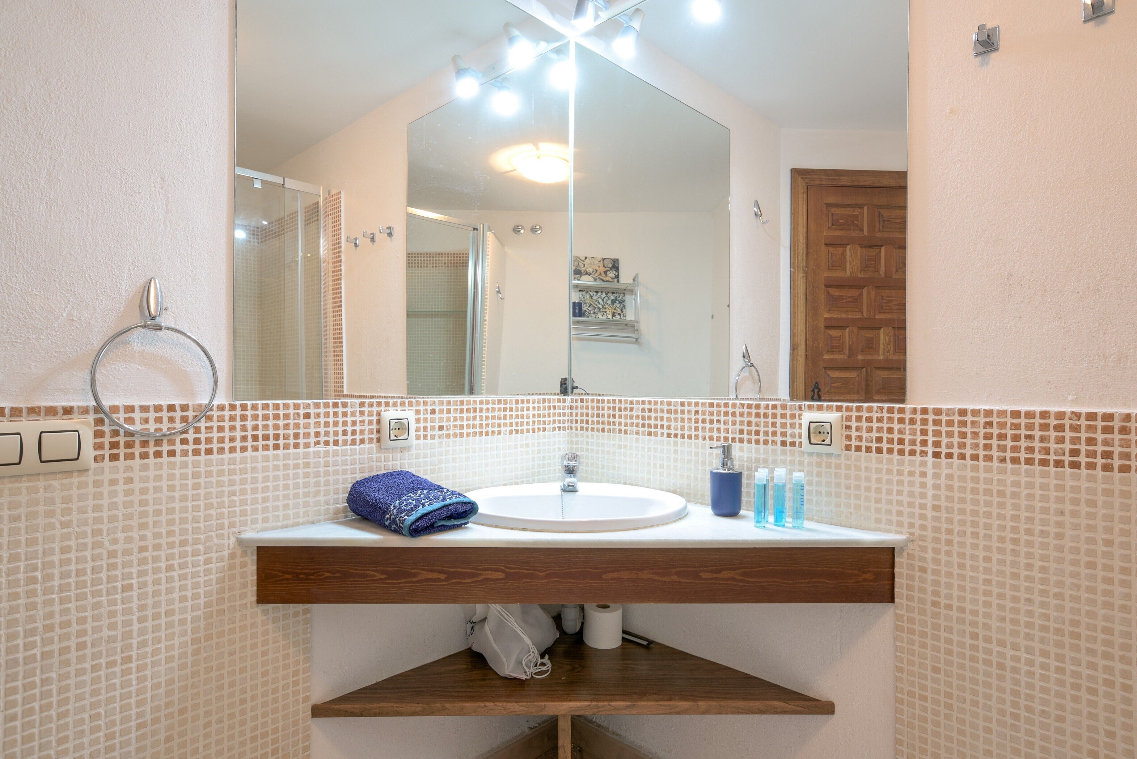 Un baño con lavamanos blanco, un espejo y una ducha.