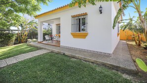Un edificio blanco con techo amarillo, un porche cubierto y un pequeño jardín.