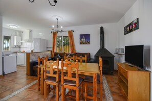 Een moderne keuken met witte kastjes, een eethoek met houten meubels, en een open haard.