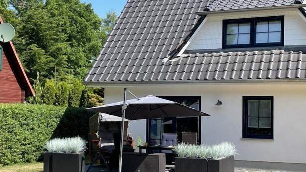 Una casa moderna con tetto in tegole, un patio con mobili da esterno e un'antenna parabolica.