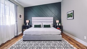 Un dormitorio moderno con una cama, mesitas de noche, ventilador de techo y una alfombra estampada.
