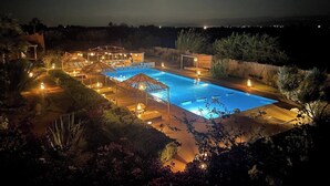 A nighttime view of a resort with a swimming pool, outdoor seating areas, and a well-lit patio. - LA SIESTA, 18 rooms, 41 sleeps for your event in Marrakech (Marrakech)