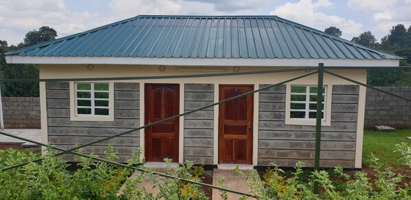 A small, single-story building with a metal roof and two wooden doors. - Oakridge Gardens (Muchatha)