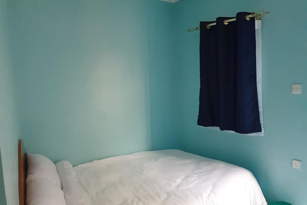 A single bed with white bedding in a room with teal walls.