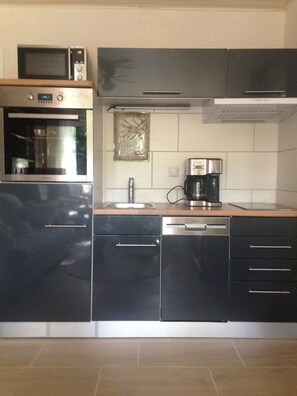 A modern kitchen with stainless steel appliances, a coffee maker, and a decorative backsplash.