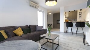 A modern living room with a sofa, coffee table, and a kitchen area in the background. - Luxury Travel Station - Pula (Pula)