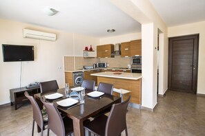 Een moderne keuken met inbouwapparatuur, een eethoek met een tafel voor vier personen en een flatscreen televisie aan de muur.