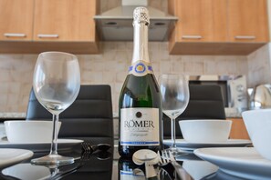 A bottle of RÖMER Krönung wine with two empty wine glasses on a table in a kitchen setting. - Apt. Toni, Modern 1BDR Ayia Napa Apt with Communal Pool, Close to Nissi Avenue (Ayia Napa)