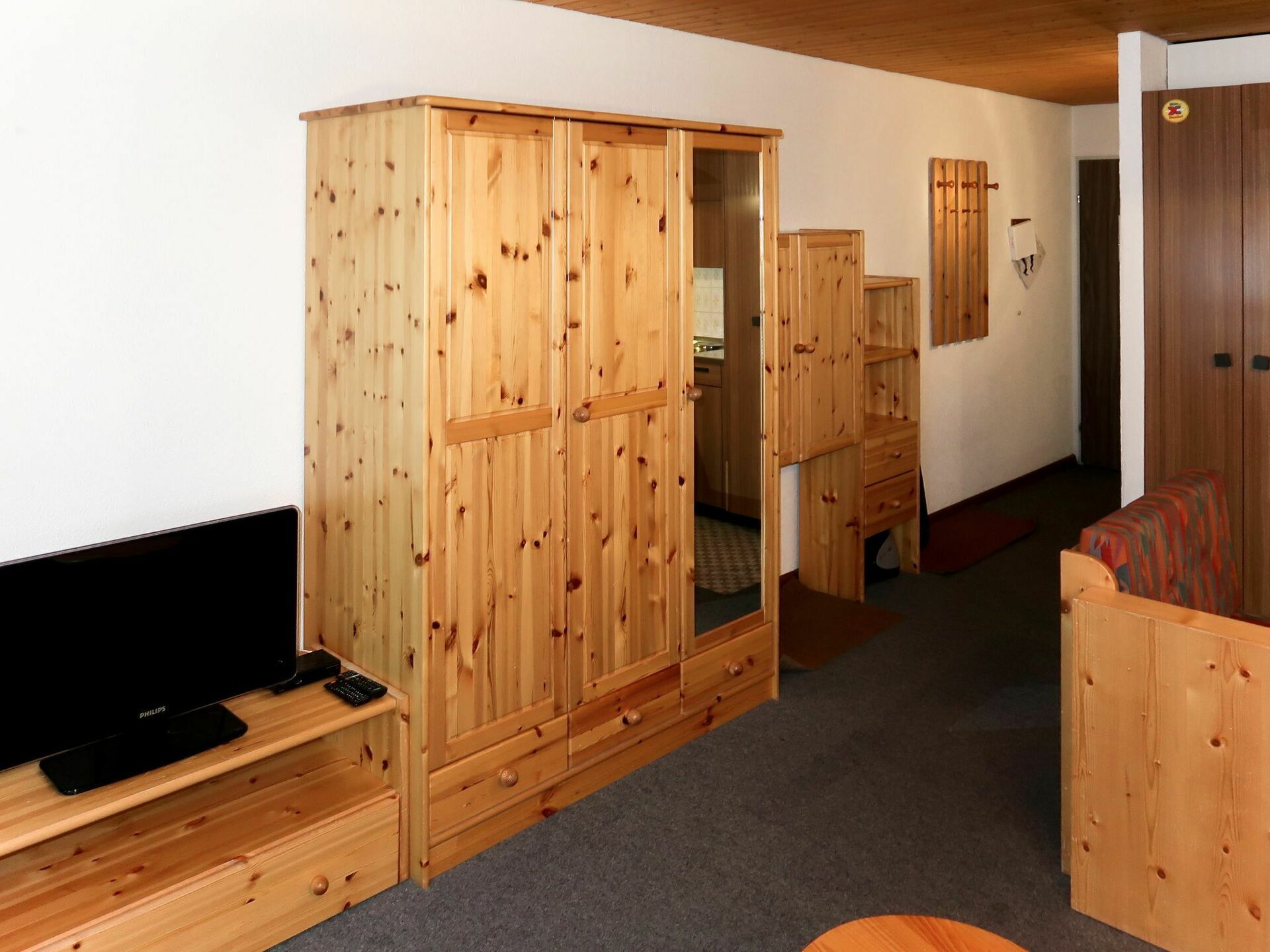 A wooden room with a wardrobe, a television on a stand, and a small table.