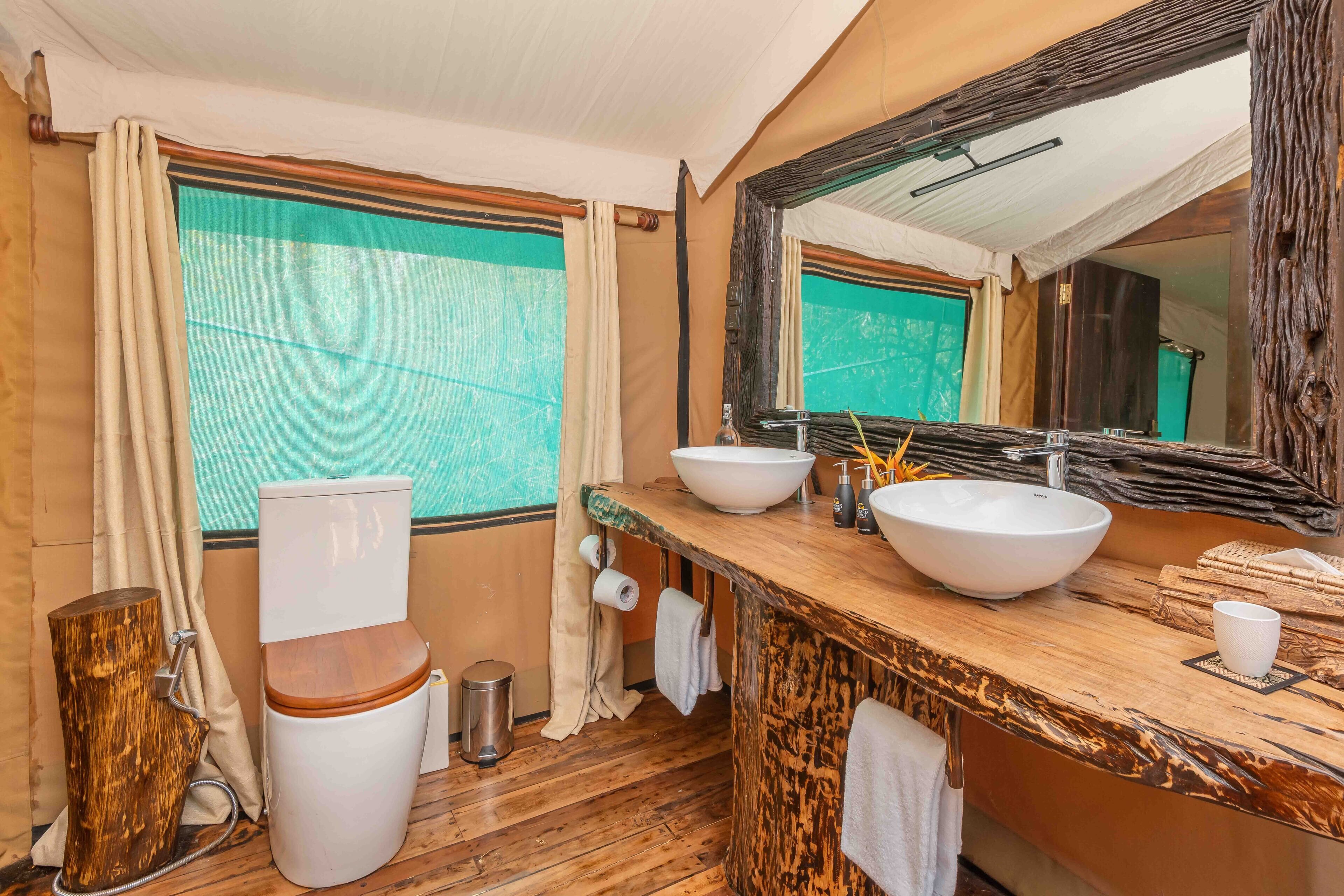 A bathroom with a wooden vanity, two sinks, a large mirror, and a toilet.