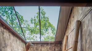 A modern bathroom with a stone wall, a wooden ladder, and a wooden table with bottles. - Leopard Safaris Yala  (Kataragama)