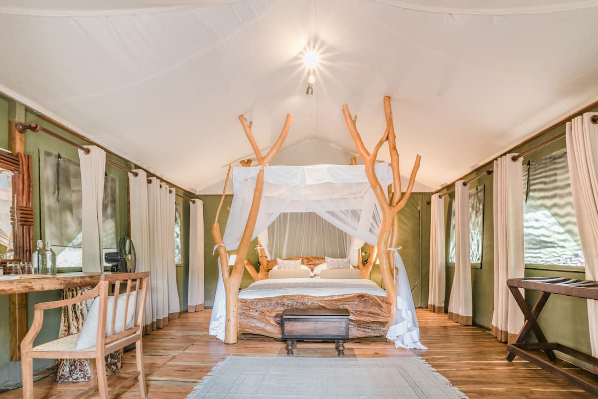 A room with a canopy bed, wooden furniture, and a view of the outdoors.