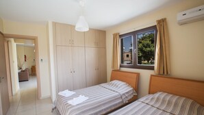 A bedroom with two beds, a wardrobe, a window with curtains, and an air conditioning unit. - Apt. Kyla, Lovely 2BDR Ayia Napa Apt with Communal Pool, Close to Nissi Avenue (Ayia Napa)
