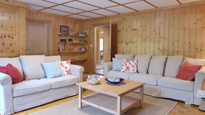 Ein gemütliches Wohnzimmer mit zwei Sofas, einem Couchtisch und einem Bücherregal aus Holz.