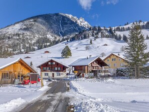 Un pueblo cubierto de nieve con casas de madera, cielo despejado y una montaña al fondo.