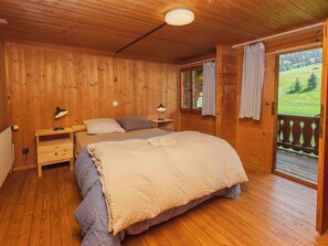 A wooden room with a bed, nightstands, and a window with curtains. - Nice apartment for 8 people with WIFI, TV, balcony and panoramic view (Schwenden Im Diemtigtal)