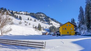 Ein gelbes Gebäude mit verschneiter Landschaft und blauem Himmel.