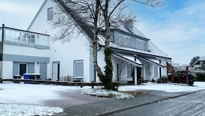 A two-story house with a sloped roof, a visible chimney, and a small tree in front. - Lovely apartment for 2 guests with WIFI, TV and terrace (Norden)