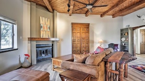 A cozy living room with a fireplace, wooden ceiling beams, a sofa, and a coffee table. - Adventurers' Oasis - 3 Mi South of Dtwn Santa Fe! (Santa Fe)