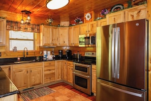 A kitchen with wooden cabinets, stainless steel appliances, a refrigerator, a microwave, and a coffee maker.