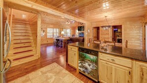 Interior de una cabaña de madera con cocina, suelo de madera y zona de comedor.
