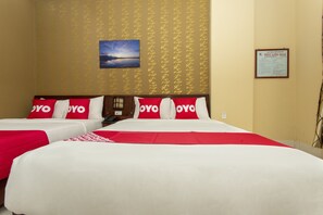 Una habitación de hotel con dos camas, cada una con ropa de cama roja y blanca, y un cuadro enmarcado en la pared.