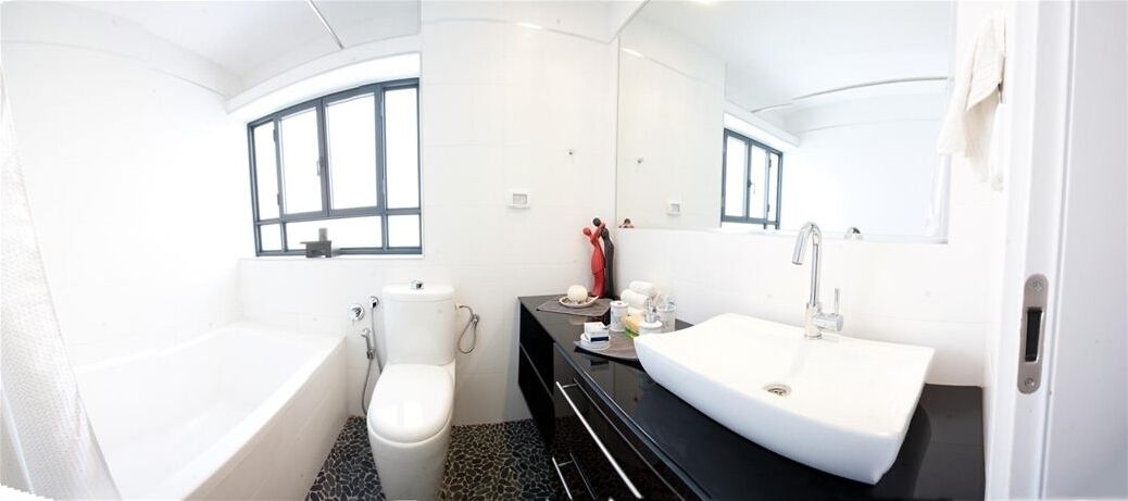 A bathroom with a bathtub, toilet, and a sink with a mirror above it.