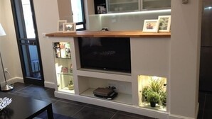 A modern living room with a flat-screen TV, built-in shelves, and a small plant display.