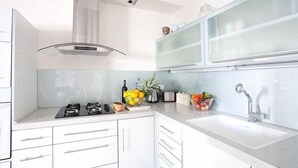A modern kitchen with white cabinets, a stainless steel sink, and a gas stove.