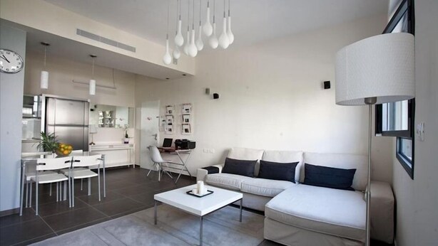 A modern living room with a white sofa, a coffee table, and a dining area with a white table and chairs.