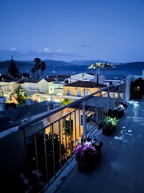 A balcony with a view of a coastal town at dusk. - Hotel Electra (Nafplio)