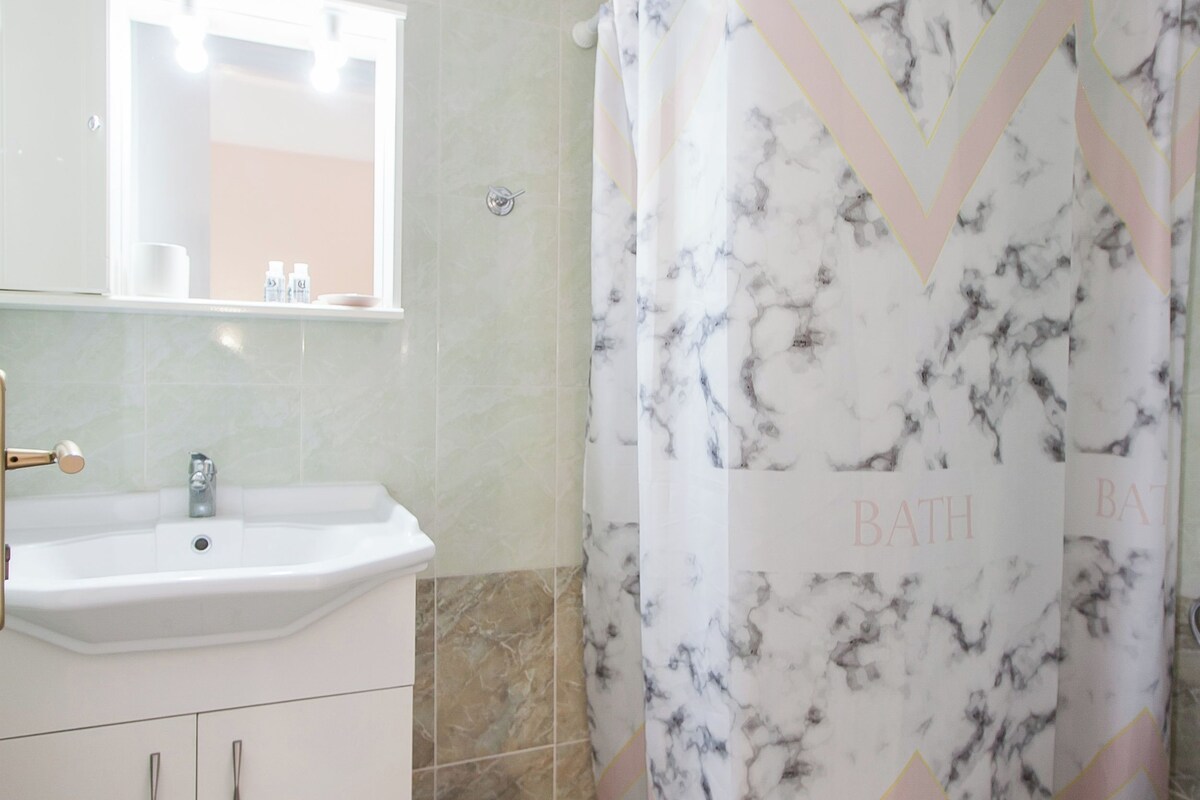 A bathroom with a sink, mirror, toilet, and shower curtain.