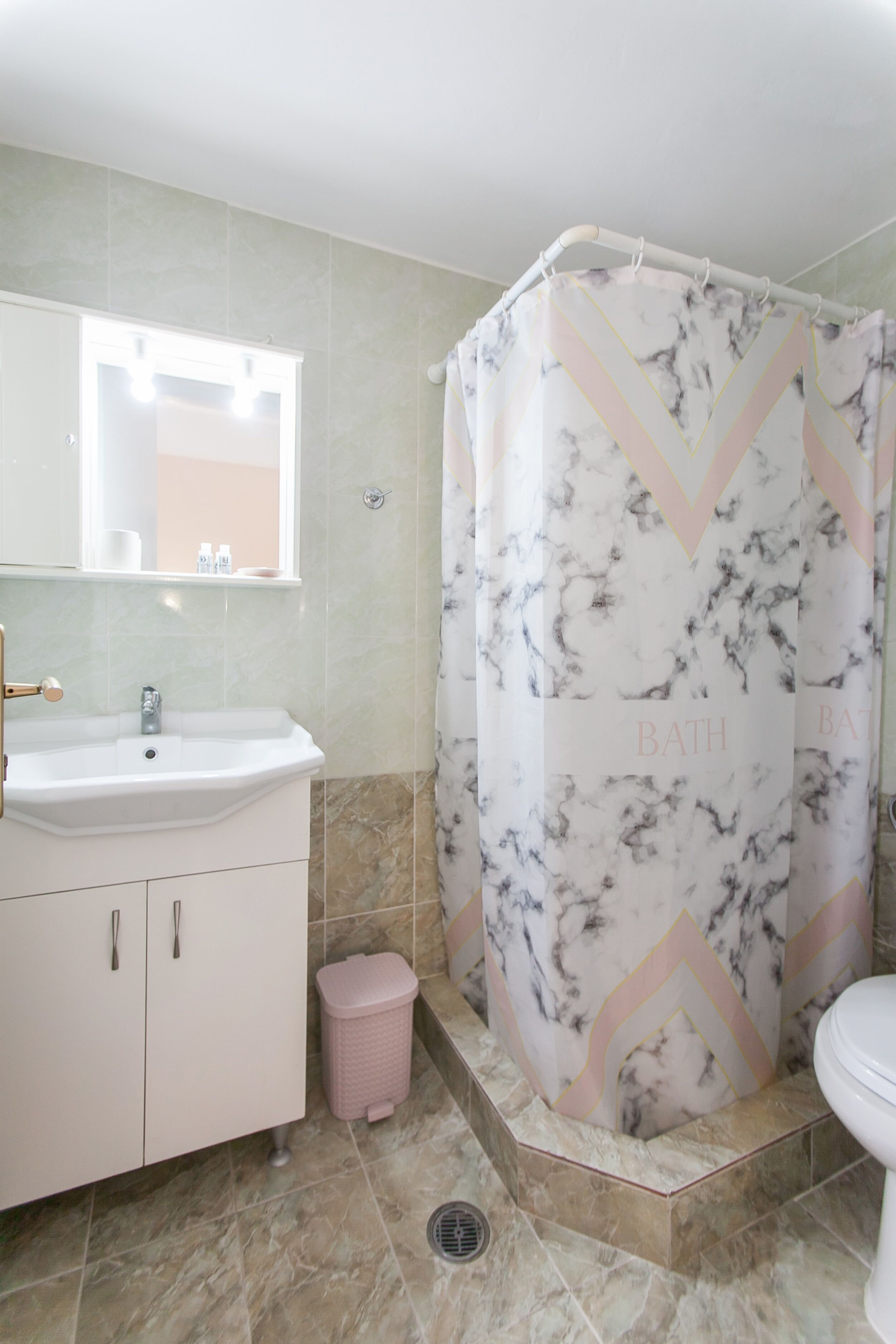 Une salle de bain équipée d’un lavabo, d’un miroir, de toilettes et d’un rideau de douche.