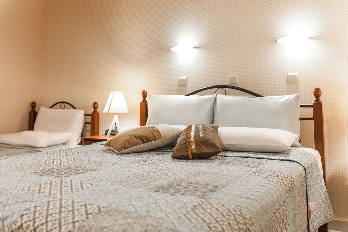 A neatly made bed with a patterned bedspread, two pillows, and a wooden headboard.