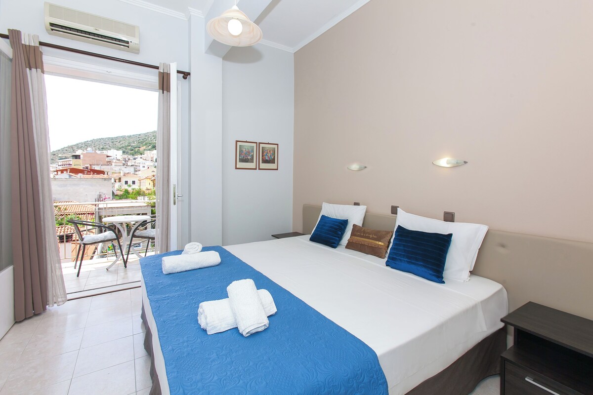 A hotel room with a bed, a balcony, and a view of the city.