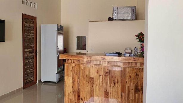 Een keuken met een houten aanrecht, een koelkast, een aan de muur bevestigde televisie en een klein schap met decoratieve objecten.